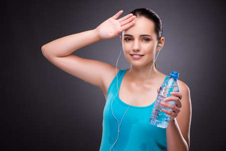 Woman doing sports with bottle of fresh waterの写真素材