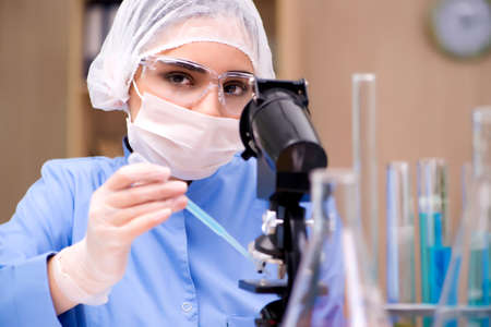 Lab chemist working with microscope and tubes