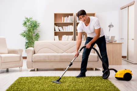 Man cleaning home with vacuum cleanerの写真素材
