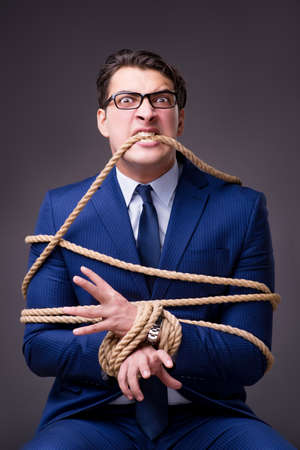 Businessman tied up with ropeの写真素材