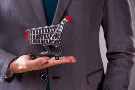 Businessman holding shopping cart in business conceptの写真素材