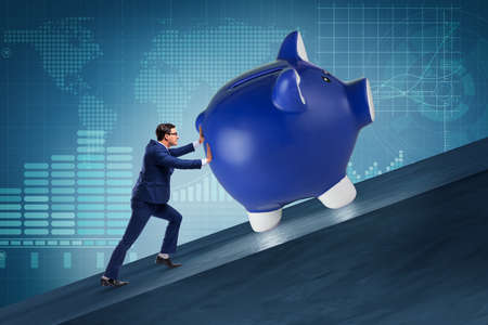 Man pushing piggybank uphill in business conceptの写真素材