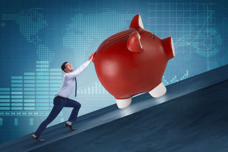Man pushing piggybank uphill in business conceptの写真素材