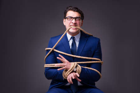 Businessman tied up with ropeの写真素材