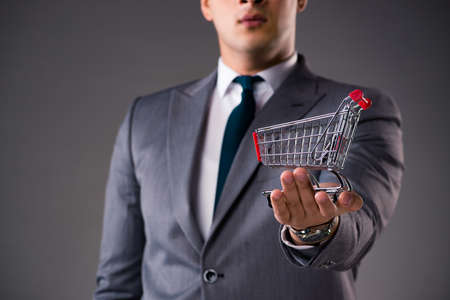 Businessman holding shopping cart in business conceptの写真素材