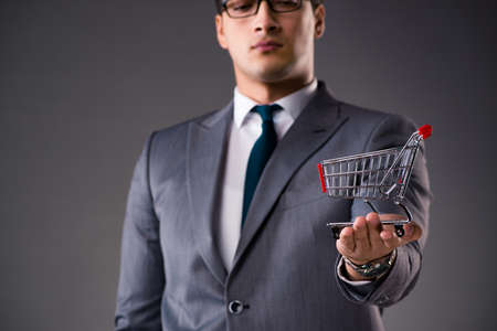 Businessman holding shopping cart in business conceptの写真素材