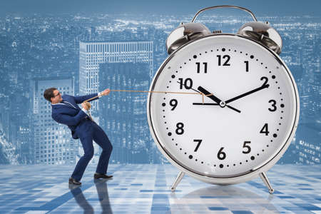 Businessman pulling clock in time management conceptの写真素材