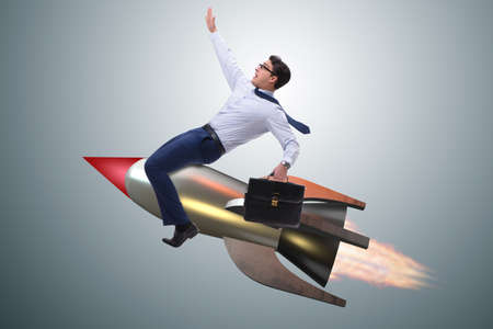 Businessman flying on rocket in business conceptの写真素材