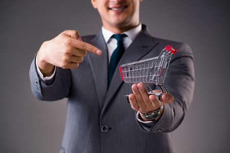 Businessman holding shopping cart in business conceptの写真素材