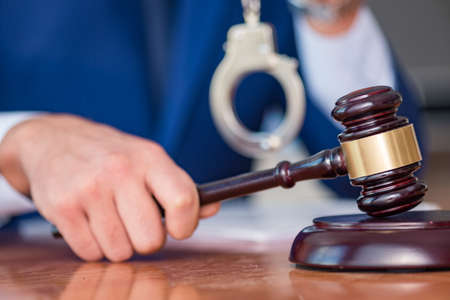 Handsome judge with gavel sitting in courtroomの写真素材