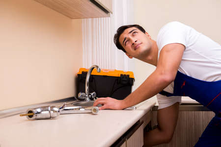 Young repairman working at the kitchenの写真素材