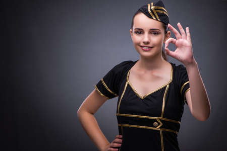 Young flight attendant on gray background