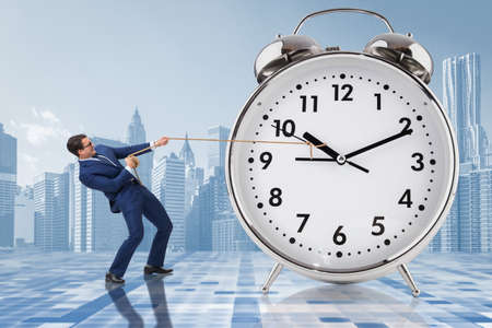 Businessman pulling clock in time management conceptの写真素材