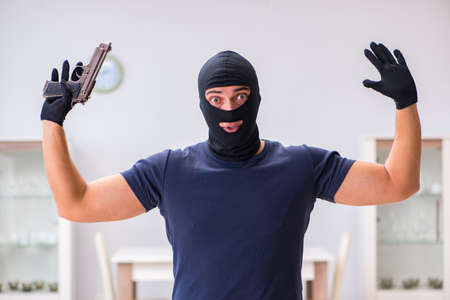 Robber wearing balaclava stealing valuable things