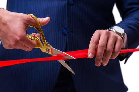 Businessman cutting red ribbon isolated on white