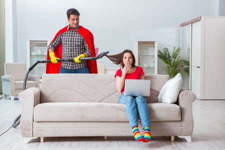 Superhero husband helping his wife at homeの写真素材