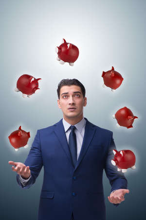 Businessman juggling with piggybanks in business conceptの写真素材