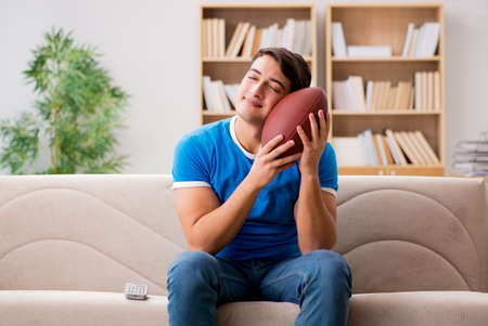 Man watching football at home sitting in couchの写真素材