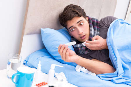 Sick man with flu lying in the bedの写真素材