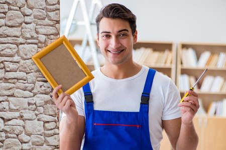 Repairman putting picture frame onto wallの写真素材