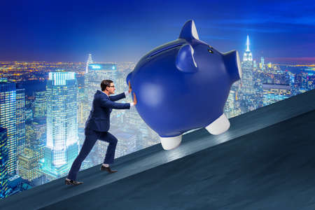 Man pushing piggybank uphill in business conceptの写真素材