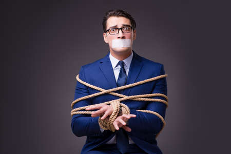Businessman taken hostage and tied up with ropeの写真素材