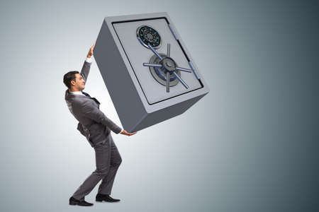 Businessman carrying metal safe in security conceptの写真素材