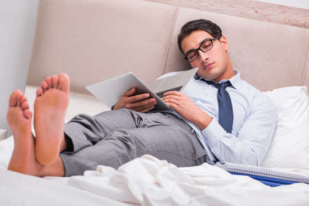 Businessman working in the bed at homeの写真素材