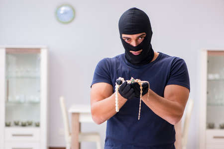 Robber wearing balaclava stealing valuable things