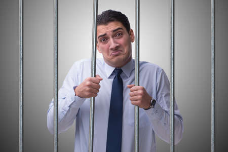 Young businessman behind the bars in prisonの写真素材