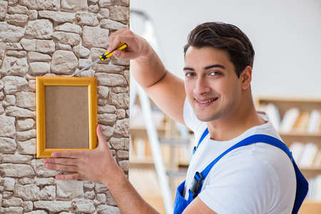 Repairman putting picture frame onto wall