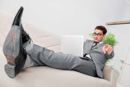 Young businessman lying on the sofaの写真素材