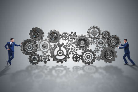 Businessman pushing cog wheels in business conceptの写真素材