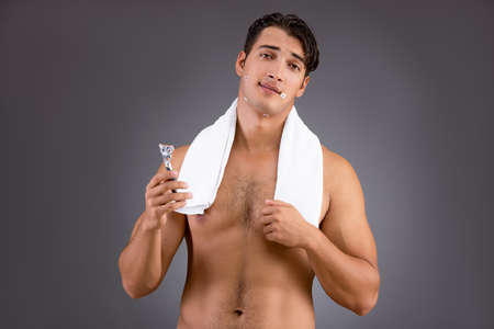 Handsome man shaving against dark backgroundの写真素材