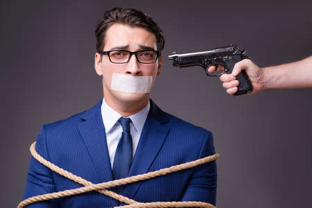 Businessman taken hostage and tied up with ropeの写真素材