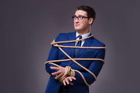Businessman tied up with ropeの写真素材