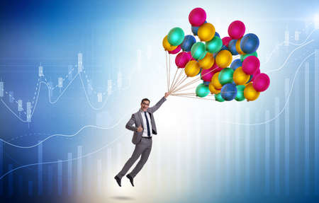Businessman flying on balloons over graphの写真素材
