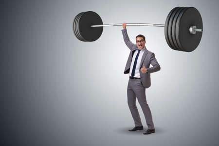 Businessman with barbell in heavy lifting conceptの写真素材