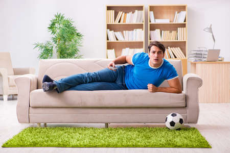 Man watching football at home sitting in couchの写真素材