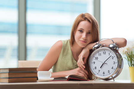 Student with gian alarm clock preparing for examsの写真素材