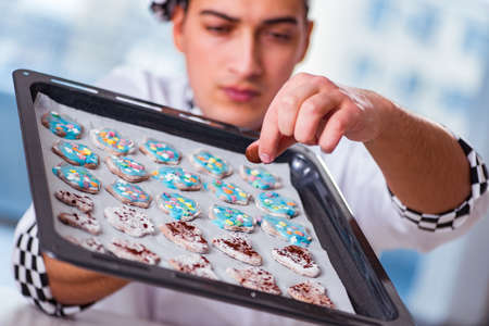 Young man cooking cookies in kitchenの写真素材