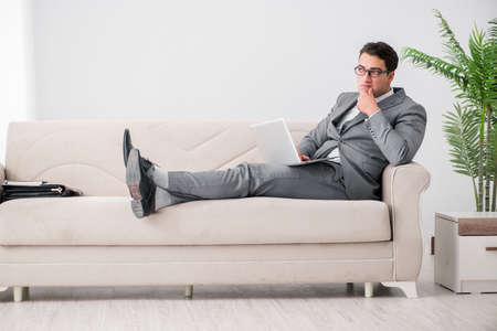 Young businessman lying on the sofaの写真素材
