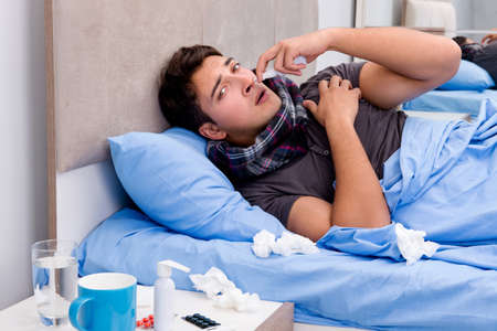 Sick ill man in the bed taking medicines and drugsの写真素材