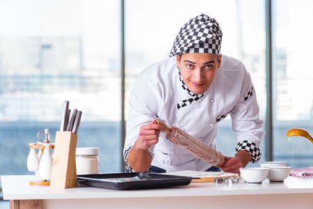 Young man cooking cookies in kitchenの写真素材