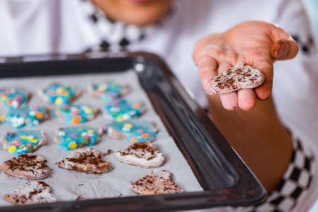 Young man cooking cookies in kitchenの写真素材