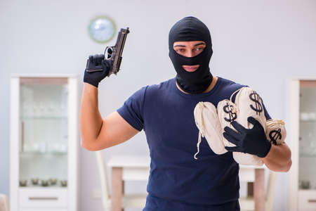Robber wearing balaclava stealing valuable things