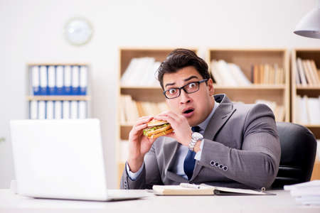 Hungry funny businessman eating junk food sandwichの写真素材