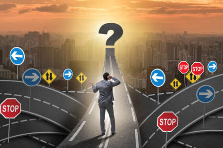 Businessman in uncertainty concept on road intersection crossroadsの写真素材