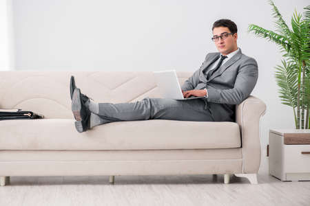 Young businessman lying on the sofaの写真素材