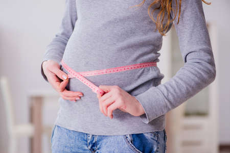 Pregnant woman measuring belly with centimeterの写真素材